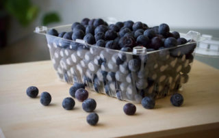 Blueberries in a plastic container on a wooden table.